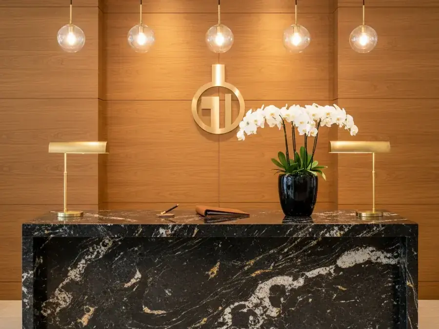 Boutique hotel reception desk with long polished black galaxy granite countertop and mitered waterfall ends